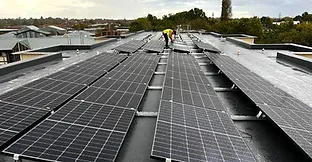 Large roof with flat roof mounted solar panels on commercial building